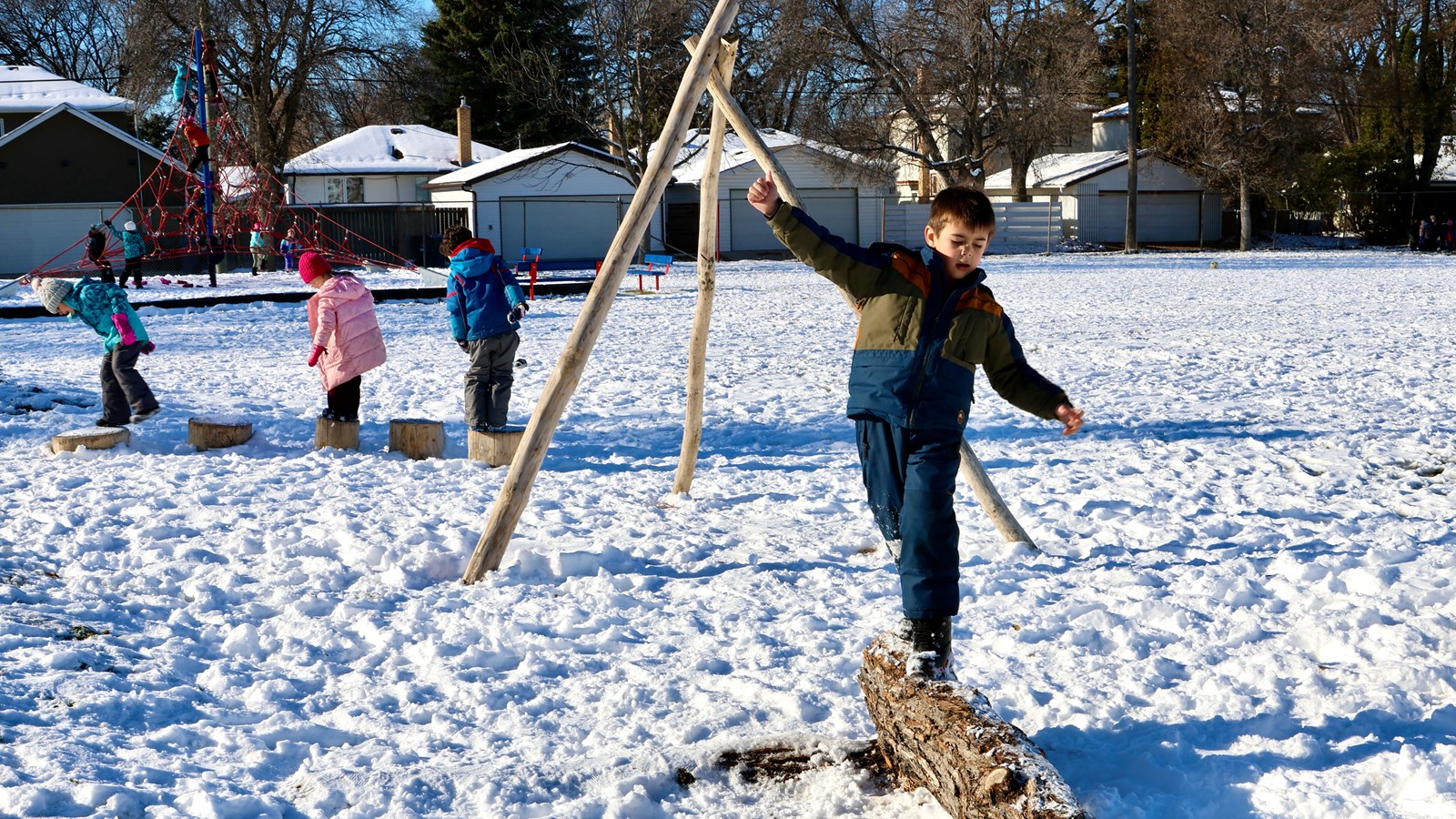 Students playing on natural elements in school yard