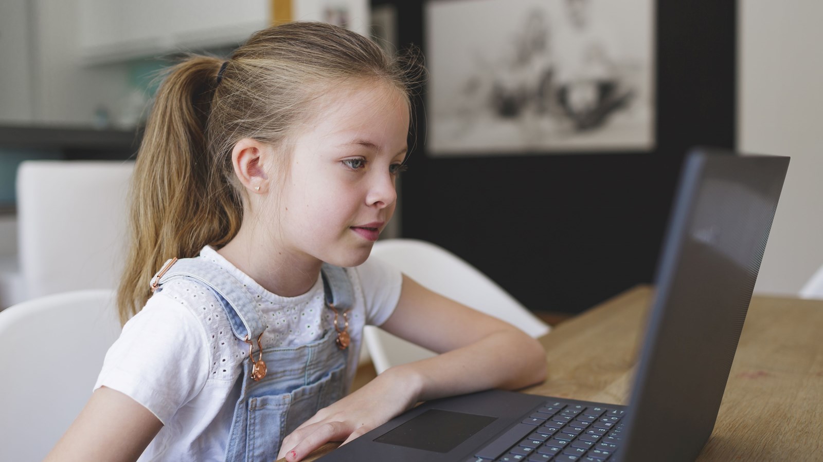 girl sitting in front of her laptop during home schooling and having an e-learning lesson